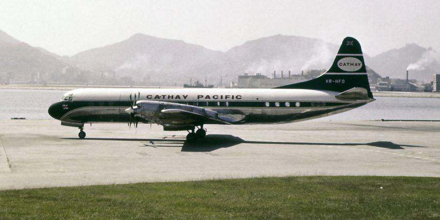 一张颗粒感强烈的复古照片,呈现一架国泰航空飞机停在跑道上,背景是连绵的山峦。